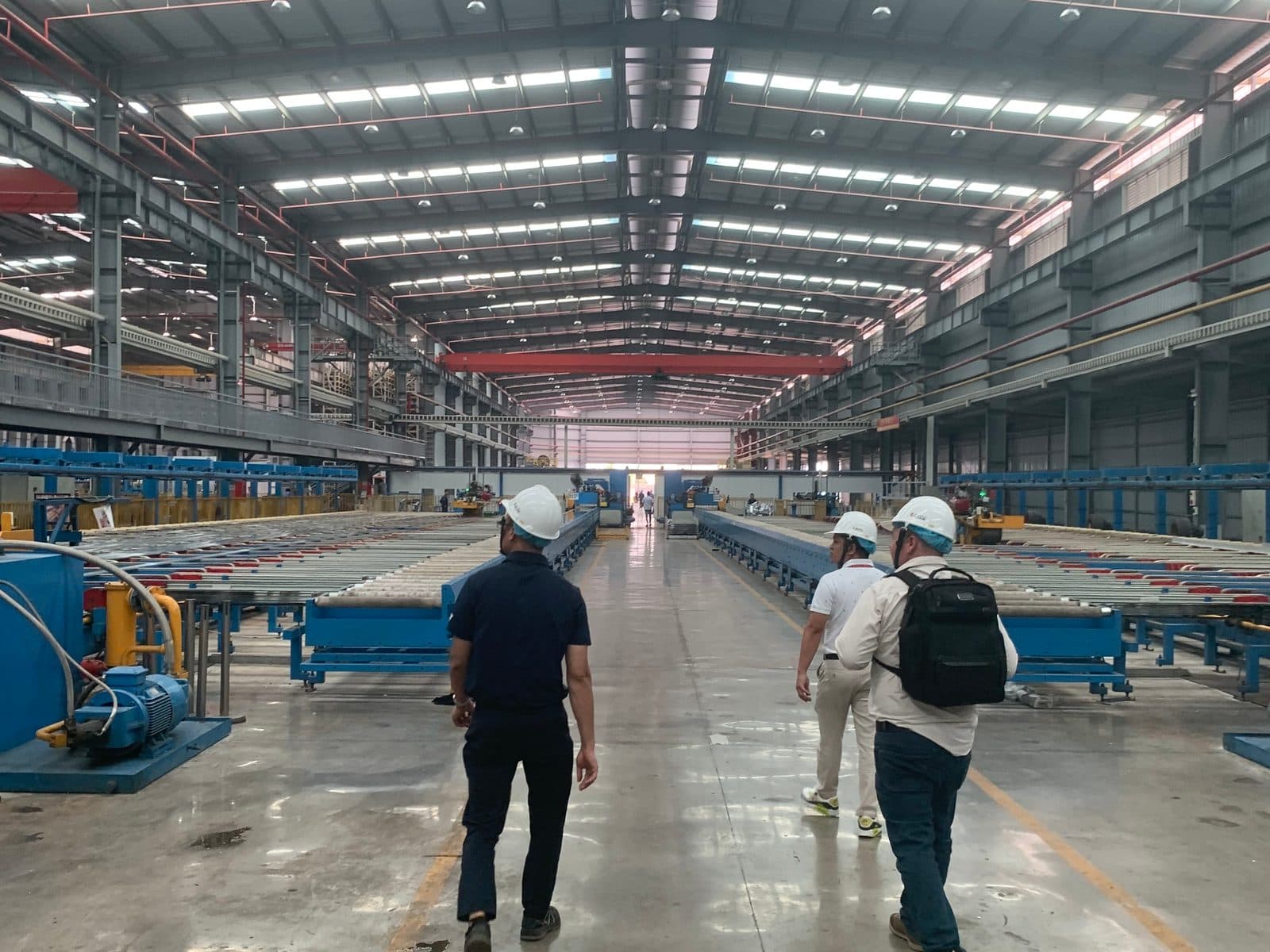 Three visitors walking through a metal manufacturing plant