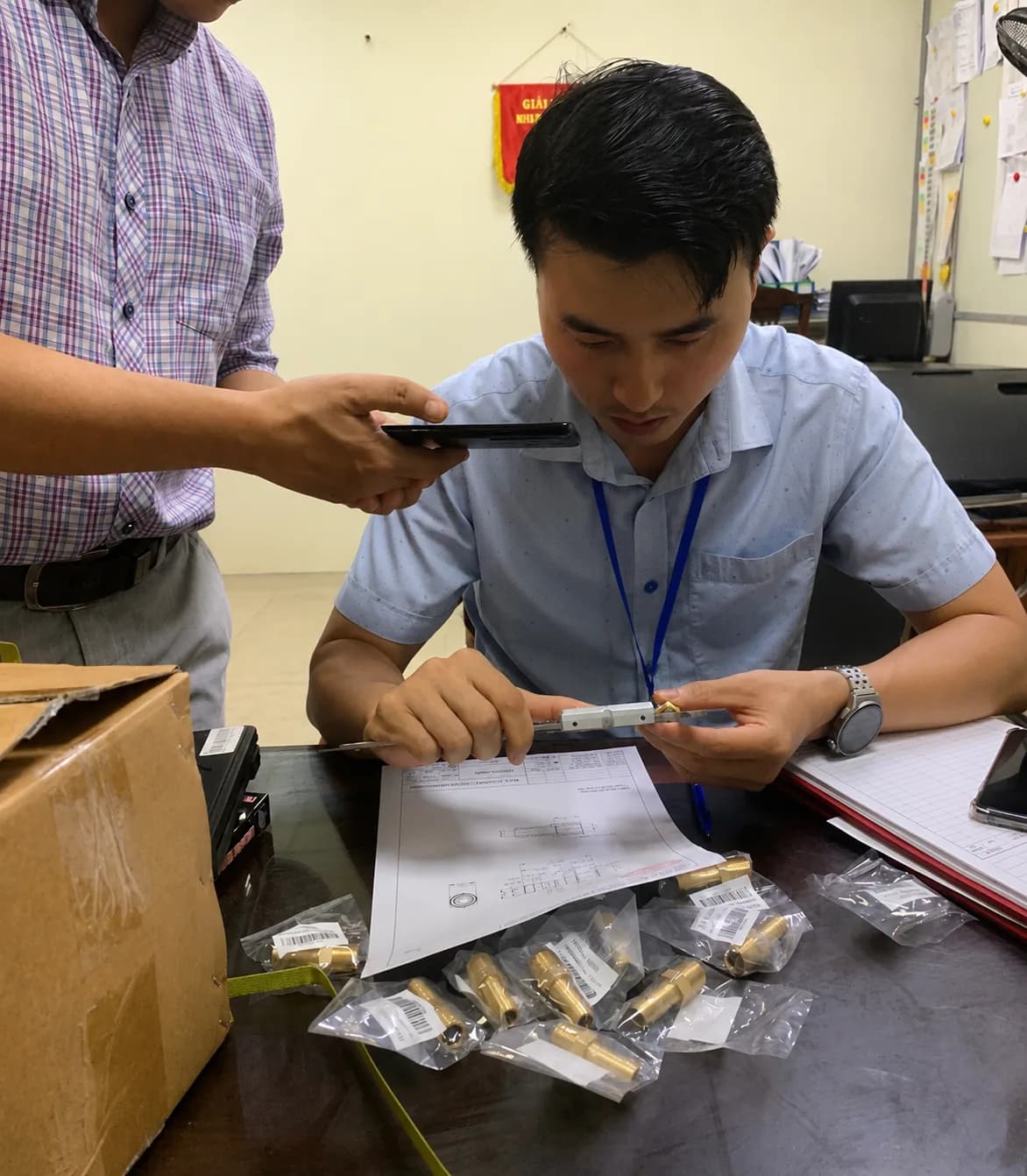 Inspector measuring a brass component with digital calipers